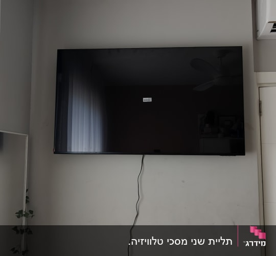 טלוויזיה תלויה על קיר עם כבל חשמל